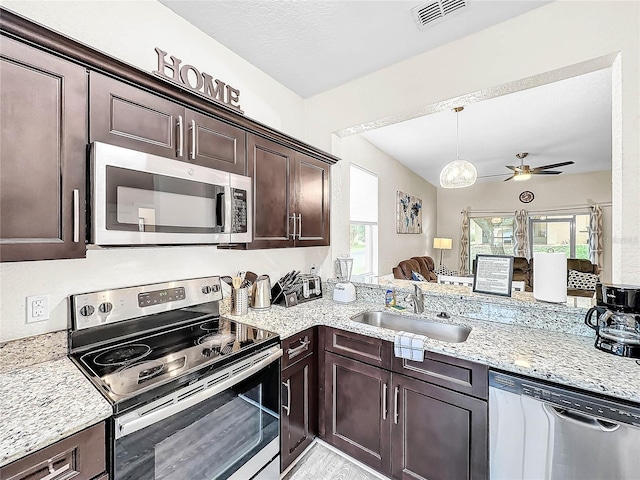 kitchen featuring stainless steel appliances, sink, dark brown cabinets, light stone countertops, and ceiling fan