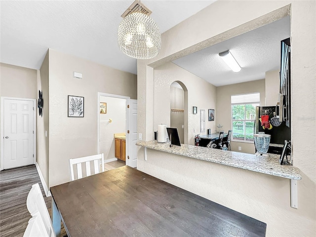 kitchen featuring decorative light fixtures, light stone countertops, dark hardwood / wood-style floors, and a textured ceiling