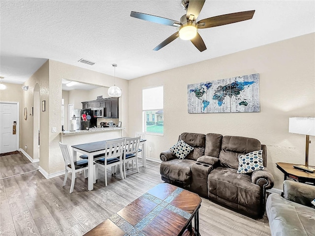 living room featuring ceiling fan, hardwood / wood-style flooring, and a textured ceiling