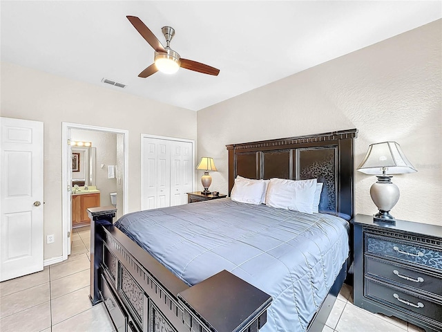 bedroom with a closet, light tile patterned floors, ensuite bath, and ceiling fan