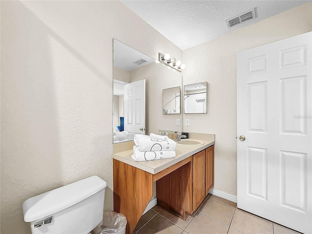 bathroom with vanity, toilet, tile patterned floors, and a textured ceiling