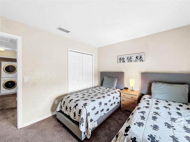 bedroom featuring stacked washer / drying machine, a closet, and dark colored carpet