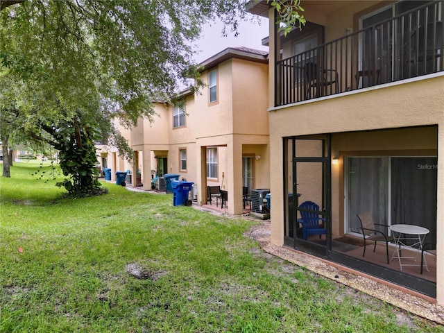 rear view of property featuring a yard, a patio, and a balcony