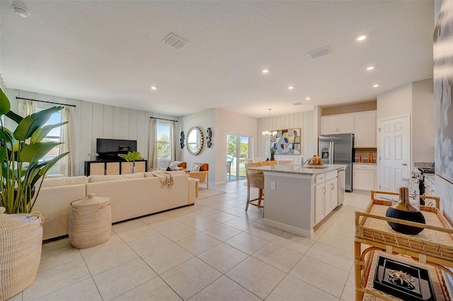 kitchen featuring hanging light fixtures, white cabinets, stainless steel fridge with ice dispenser, and a center island