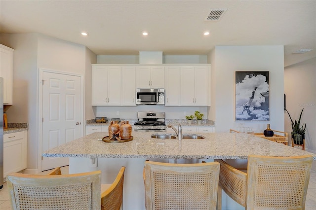 kitchen with stainless steel appliances, white cabinets, and a kitchen island with sink