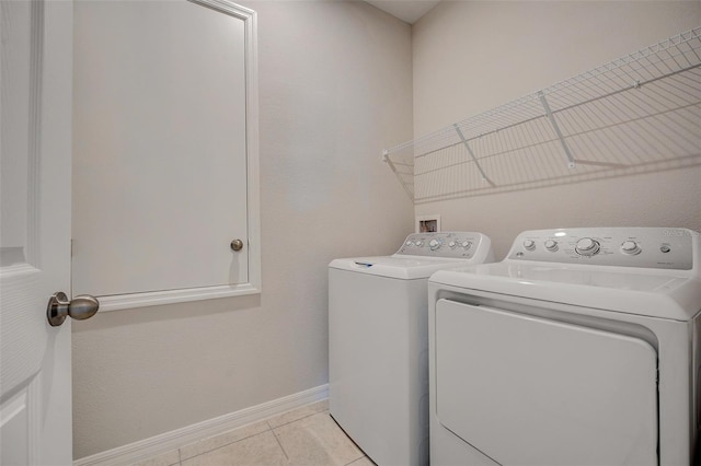 clothes washing area featuring washer and dryer and light tile patterned floors