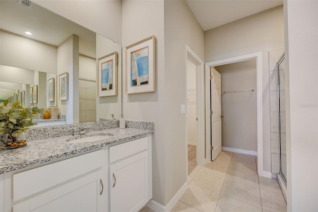 bathroom with walk in shower, vanity, and tile patterned flooring