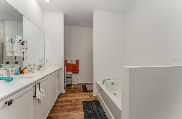 bathroom featuring dual vanity, hardwood / wood-style flooring, and a washtub