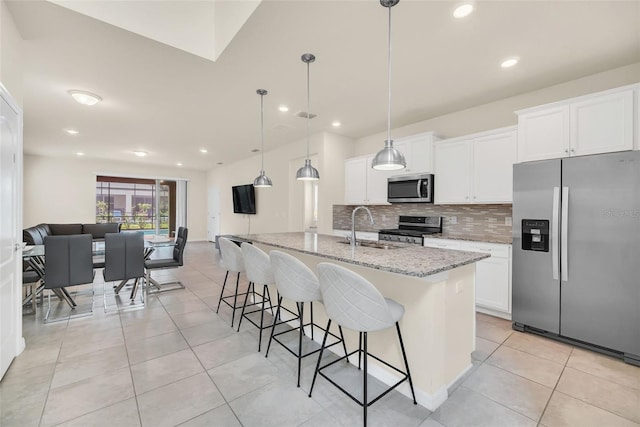 kitchen with appliances with stainless steel finishes, light stone countertops, tasteful backsplash, and white cabinetry