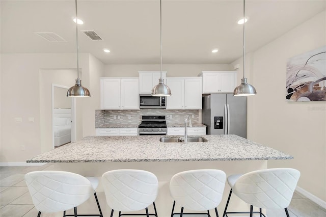 kitchen with sink, a large island with sink, tasteful backsplash, and stainless steel appliances