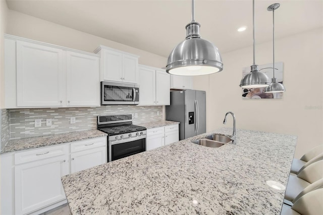 kitchen featuring white cabinets, stainless steel appliances, hanging light fixtures, decorative backsplash, and sink