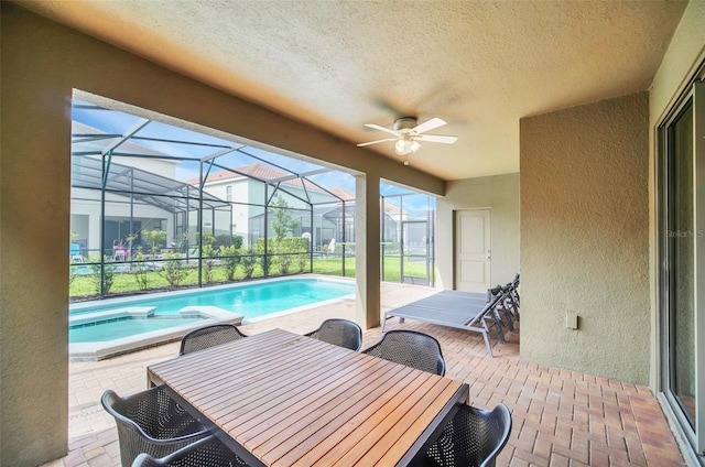 exterior space featuring a patio area, ceiling fan, and glass enclosure