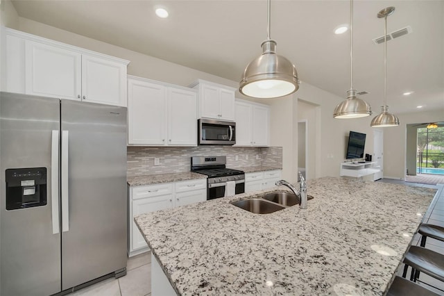 kitchen featuring stainless steel appliances, sink, backsplash, an island with sink, and white cabinetry