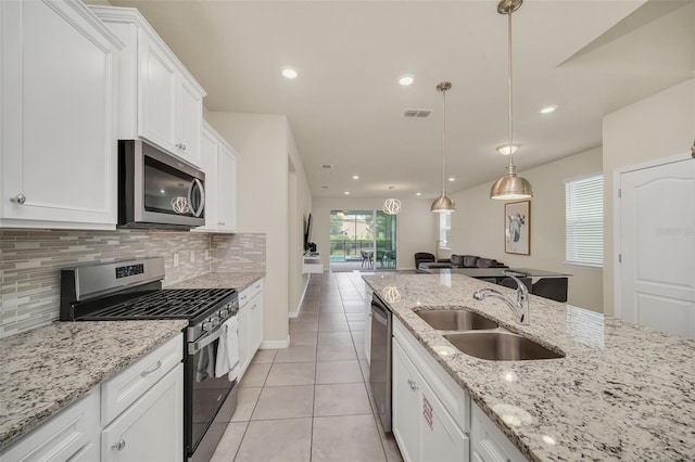 kitchen with tasteful backsplash, stainless steel appliances, sink, light tile patterned floors, and light stone countertops