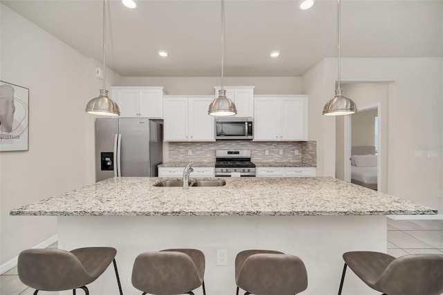 kitchen with sink, a kitchen island with sink, decorative backsplash, and stainless steel appliances