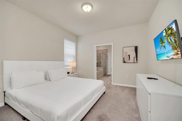 bedroom with ensuite bath and light carpet