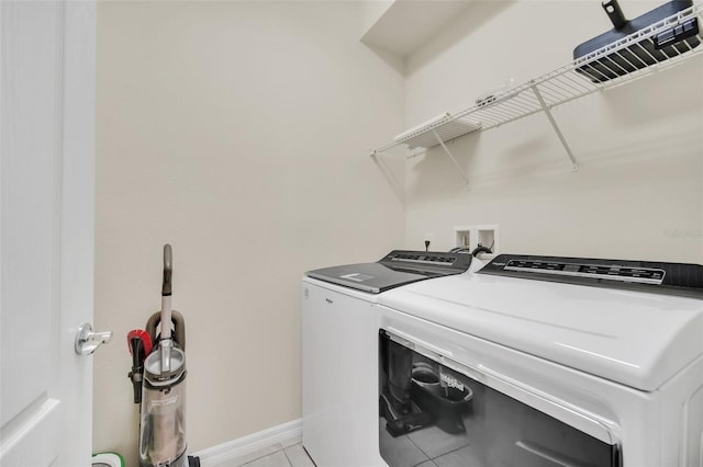 laundry area with washer and clothes dryer and light tile patterned floors