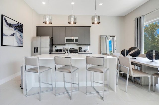 kitchen featuring a breakfast bar area, decorative light fixtures, appliances with stainless steel finishes, and light tile patterned floors