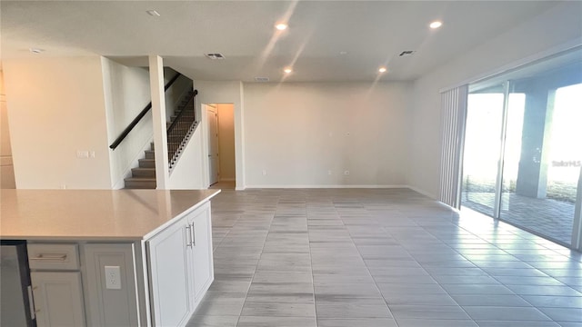 unfurnished living room with recessed lighting, visible vents, plenty of natural light, and stairs