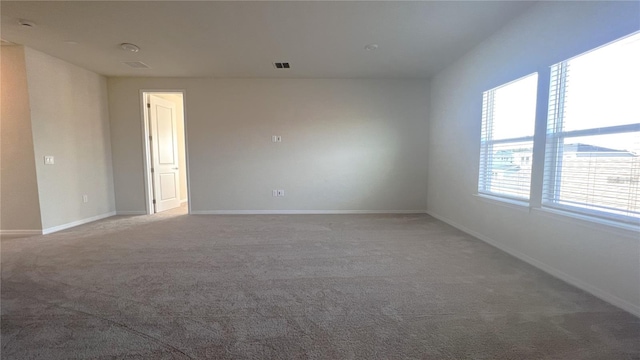 spare room with visible vents, baseboards, and carpet flooring