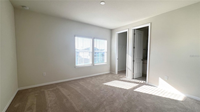 unfurnished bedroom featuring a closet, a spacious closet, and light colored carpet