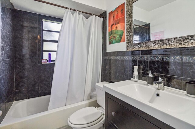 full bathroom featuring shower / bath combo with shower curtain, tile walls, backsplash, toilet, and vanity