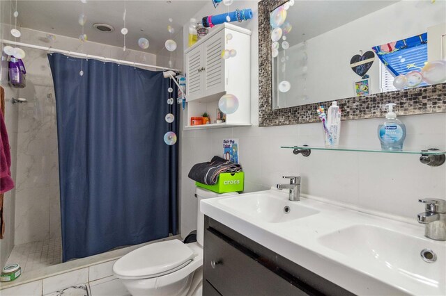 bathroom with tile walls, walk in shower, decorative backsplash, toilet, and dual bowl vanity