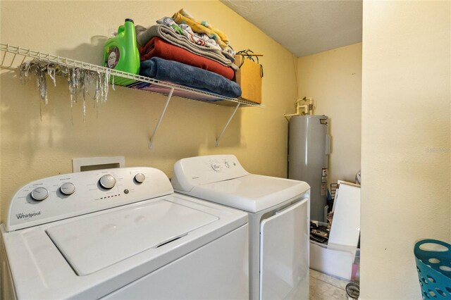 laundry area with washing machine and clothes dryer, light tile patterned floors, and water heater