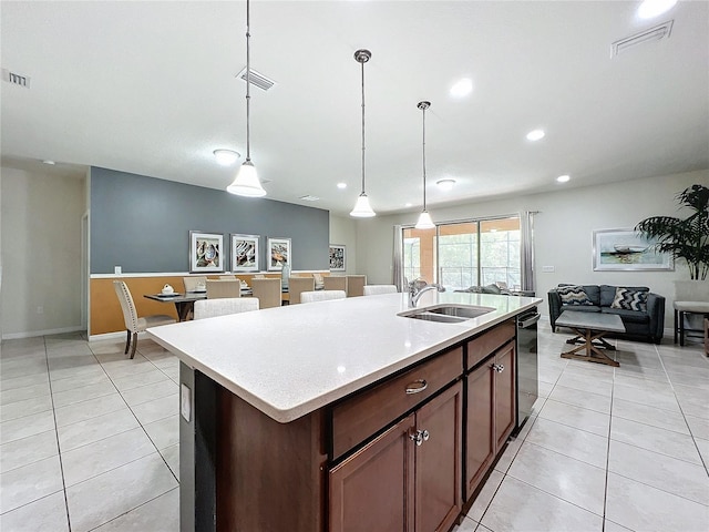 kitchen featuring decorative light fixtures, an island with sink, black dishwasher, sink, and light tile patterned floors