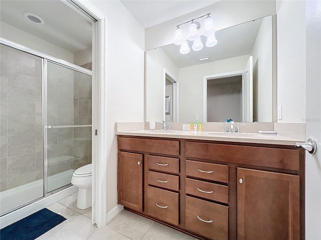 bathroom with tile patterned flooring, vanity, a shower with door, and toilet