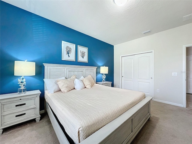 bedroom with light colored carpet, a closet, and a textured ceiling