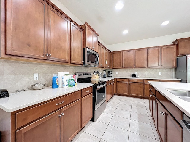 kitchen featuring tasteful backsplash, light tile patterned flooring, appliances with stainless steel finishes, and sink