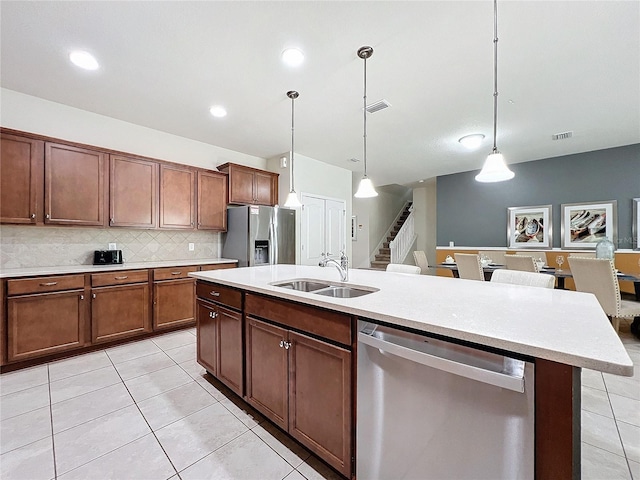 kitchen featuring pendant lighting, appliances with stainless steel finishes, sink, and a center island with sink