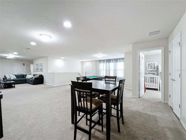 carpeted dining room with a textured ceiling