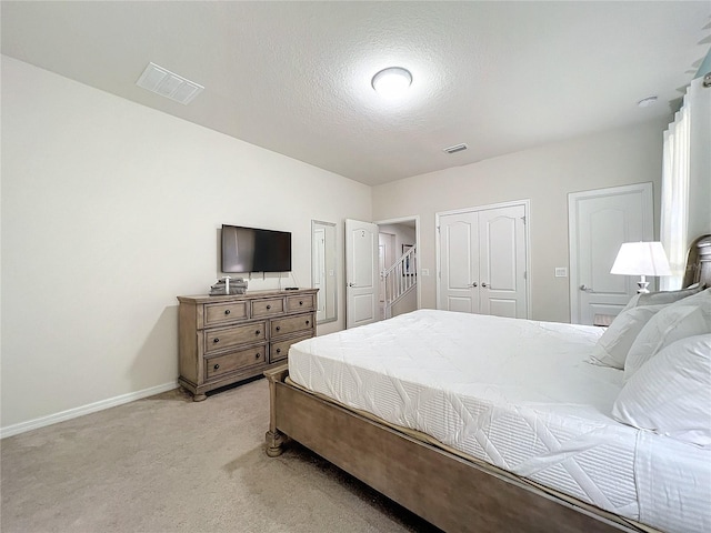 bedroom with light colored carpet and a textured ceiling