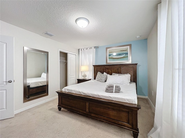 bedroom featuring light colored carpet, a textured ceiling, and a closet