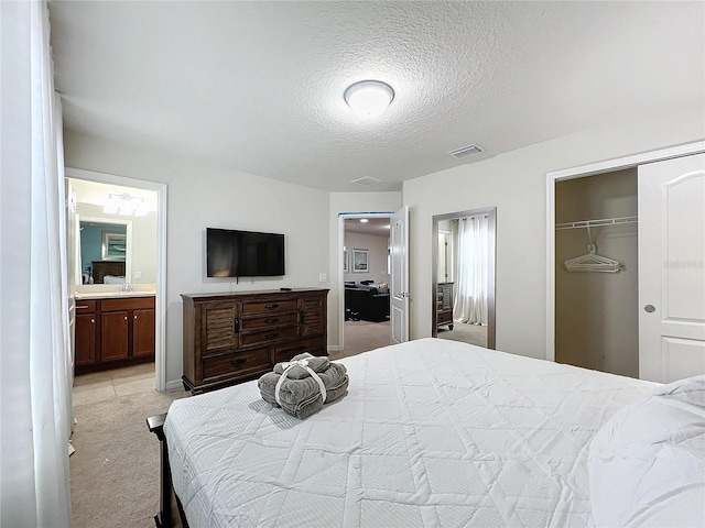 carpeted bedroom with connected bathroom, sink, a closet, and a textured ceiling