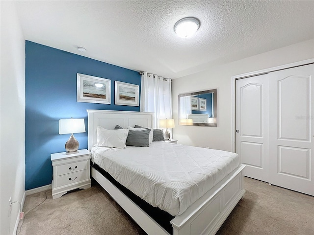 bedroom featuring a closet, light carpet, and a textured ceiling