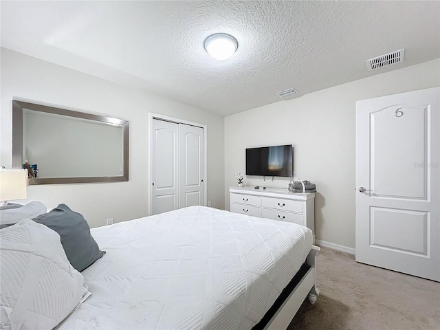 carpeted bedroom with a textured ceiling and a closet