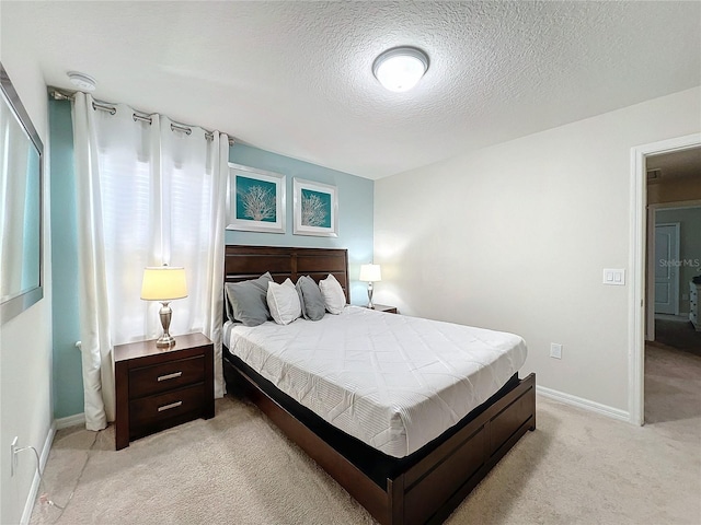 bedroom with light colored carpet and a textured ceiling