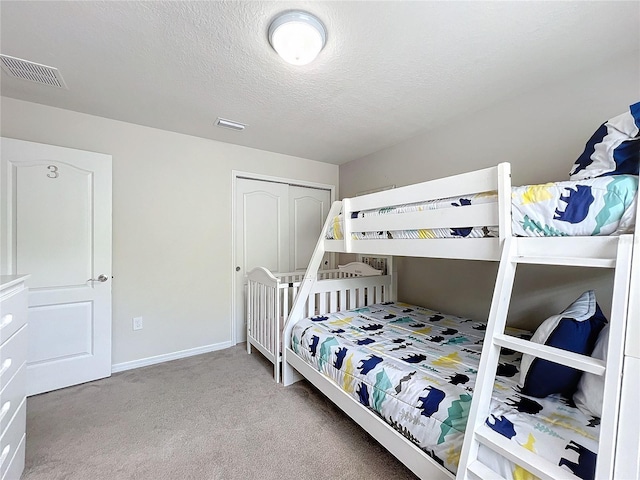 carpeted bedroom with a textured ceiling and a closet