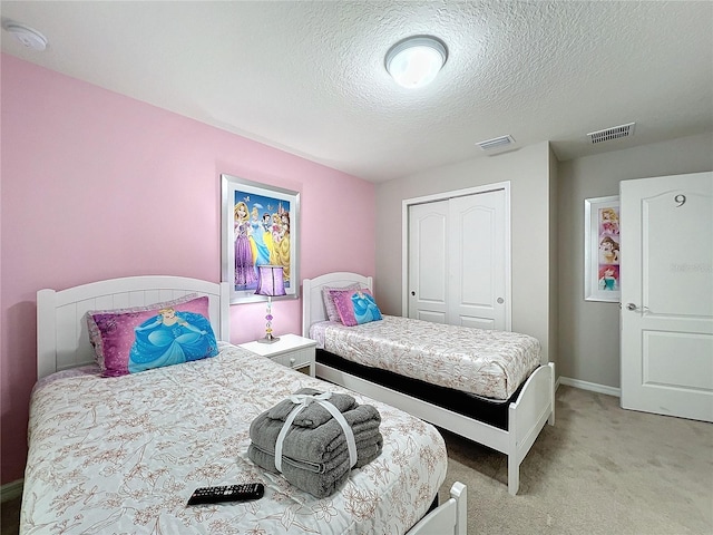 bedroom featuring light carpet, a textured ceiling, and a closet