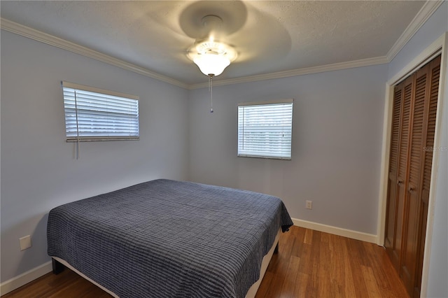 bedroom featuring wood-type flooring, a textured ceiling, a closet, and crown molding