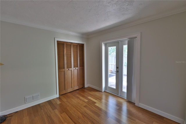 interior space with crown molding, a textured ceiling, and light hardwood / wood-style flooring