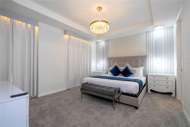 carpeted bedroom with a raised ceiling and a chandelier