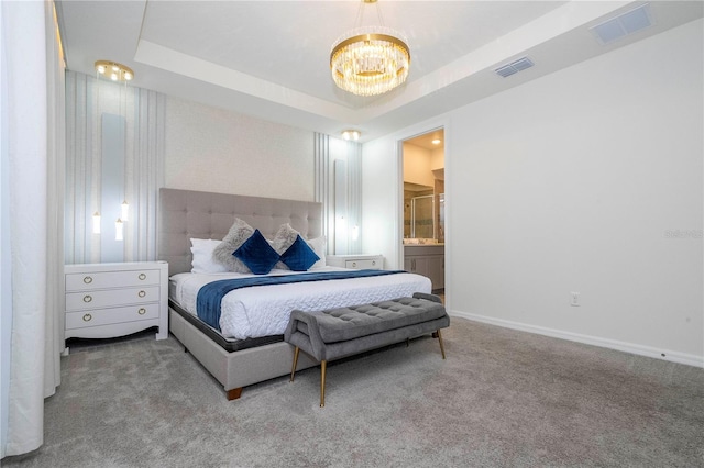 carpeted bedroom with ensuite bathroom, a raised ceiling, and a chandelier