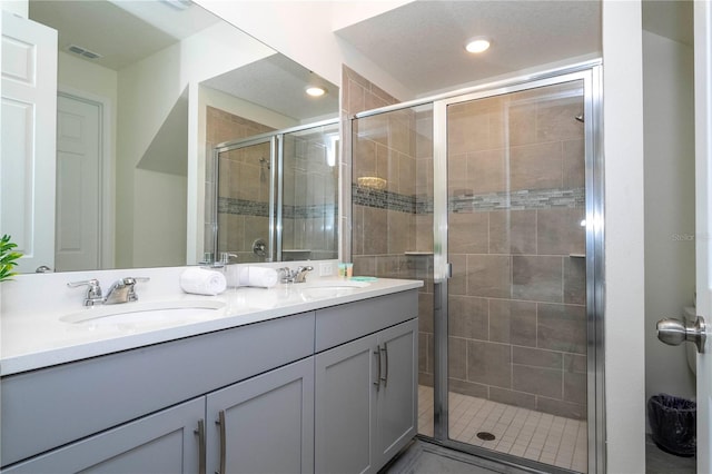 bathroom with double vanity and a shower with shower door