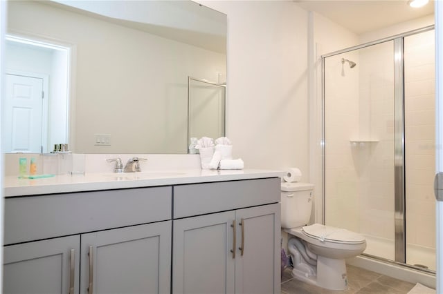 bathroom with a shower with shower door, vanity, tile patterned floors, and toilet