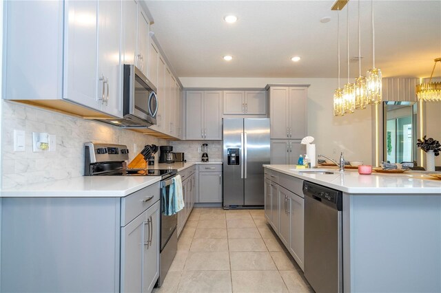 kitchen featuring tasteful backsplash, stainless steel appliances, hanging light fixtures, gray cabinets, and light tile patterned flooring