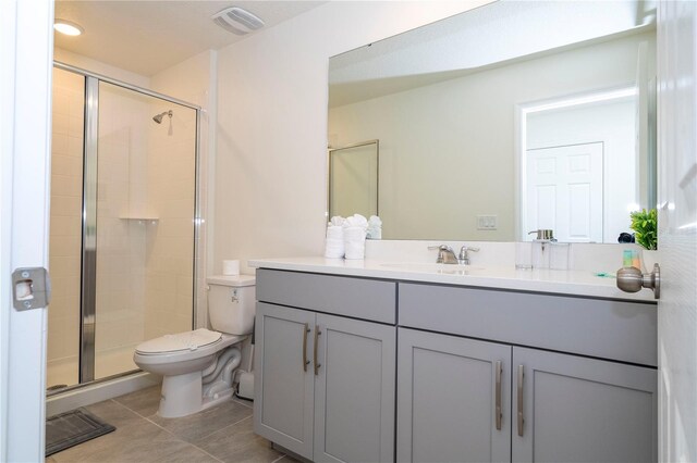 bathroom featuring vanity, a shower with shower door, toilet, and tile patterned floors